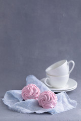 Homemade pink marshmallow on the blue linen napkin with cups