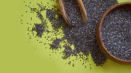 Nutritious chia seeds on a yellow background. chia seeds in bowl and a spoon on kitchen table top...