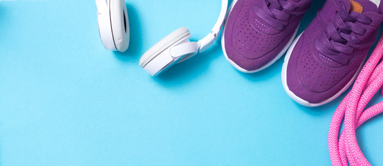 headphones, sneakers, jump rope on blue background flat lay
