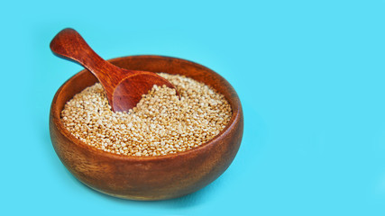 White quinoa seeds on a blue background. quinoa in bowl and a spoon on kitchen table top view. Healthy and diet superfood product.