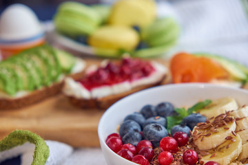 breakfast top view black background. oatmeal with berries, toasts on a wooden tray, nuts, coffee