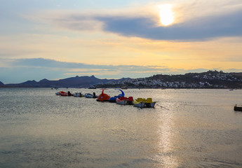 Beautiful sunset on Aegean coast with islands and mountains, boats and catamarans