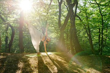 Young yogi asian attractive woman practicing yoga concept, standing in Half Moon exercise, Ardha Chandrasana pose, working out, . A woman practices yoga alone in the forest.