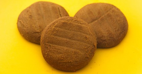 three brown chocolate cookies in a yellow plate