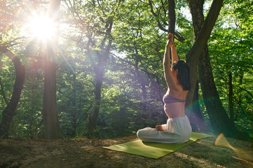Yoga woman is meditating alone. Nature background. A woman practices yoga alone in the forest. Back view. Spiritual Travel Relaxation Lifestyle Concept. Harmony with nature.