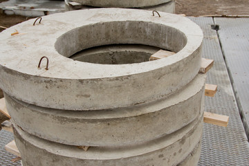 Concrete sewer rings are stacked for storage at the construction site.