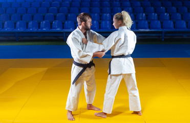 Martial arts. Sparing Portners. Sport man and woman in white kimono train judo captures in the...