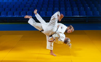 Martial arts. Sparing Portners. Sport man and woman in white kimono train judo throws and captures...