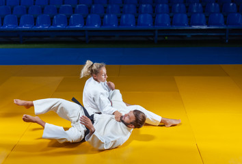 Martial arts. Sparing Portners. Sport man and woman in white kimono train judo throws and captures...