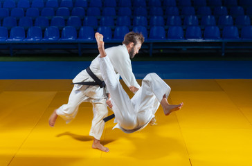 Martial arts. Sparing Portners. Sport man and woman in white kimono train judo throws and captures...