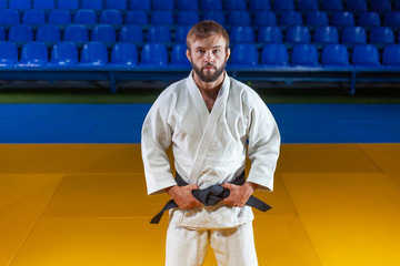 Portrait of martial artist in white kimono with black belt indoor