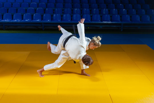 Martial arts. Sparing Portners. Sport man and woman in white kimono train judo throws and captures in the sports hall