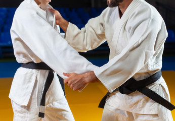Martial arts. Sparing Portners. Sport man and woman in white kimono train judo captures in the sports hall. Crop photo - obrazy, fototapety, plakaty