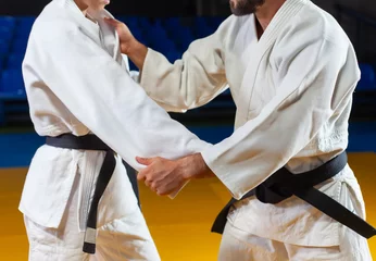 Foto op Plexiglas Martial arts. Sparing Portners. Sport man and woman in white kimono train judo captures in the sports hall. Crop photo © splitov27