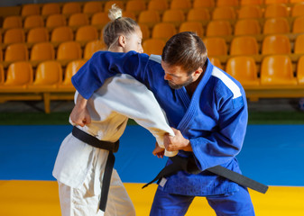 Martial arts. Sparing Portners. Sport man and woman in white and blue kimono train judo throws and...