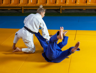 Martial arts. Sparing Portners. Sport man and woman in white and blue kimono train judo throws and...