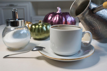 On a light table, a cup of coffee and ceramic pumpkins. Halloween