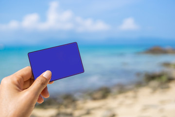 Hand holding blank credit card on beach with copy space. Tourism business concept, Shopping concept