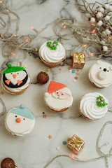 New Year's sweets on a marble table. Christmas cupcakes decorated with mastic and cream