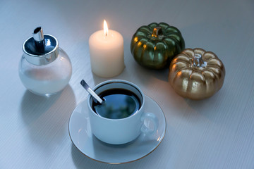 On a light table, a cup of coffee and ceramic pumpkins. Halloween