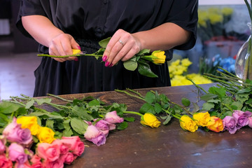 Floral business concept. Professional florist woman prepares flowers to bunch bouquet. She cuts...