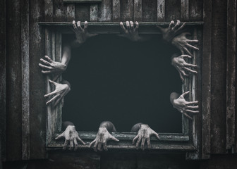 Hands rising out from the old window ancient house, Halloween concept. Increased noise and grain...