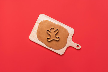 Gingerbread man cookie cutter and dough on red background