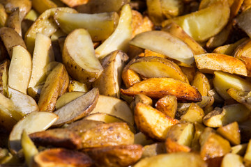 Roast potatoes in a large pan. Delicious food at the festival. Many potatoes on the table in a metal tray.