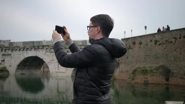 man films ancient atchitecture reflecting in river