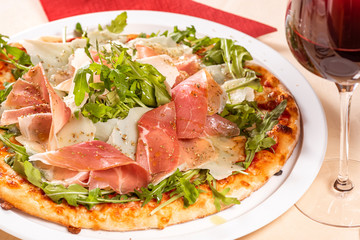 Italian Cuisine. Pizza with prosciutto, ham, arugula and parmesan