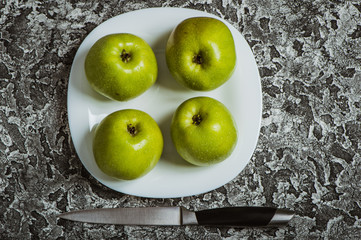 Apples in a plate than a knife. Fresh yellow apples.