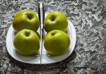 Apples in a plate than a knife. Fresh yellow apples.