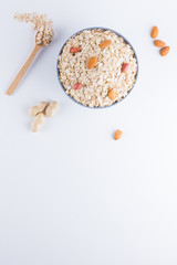 Dry oatmeal and nuts on white background. Ingredients for healthy breakfast: almonds, peanuts and oatmeal. Copy space