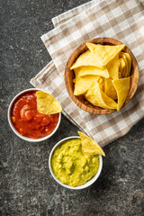Corn nacho chips with avocado and tomato dip. Yellow tortilla chips and guacamole salsa.