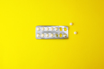 Half-empty blister with white tablets lies on a yellow background. Copy space.