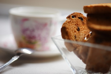 Tea time. Crackers in a glass vase, cup with tea on the blurred background.