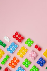 Colored toy bricks on a pink background with place for your content