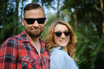 Portrait of happy smiling hipsters couple in sunglasses spending time together outdoors in the park