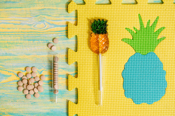 Natural plant-based diet pills, pineapple capsules. Bright pineapple candy on a gray background, crumpled paper. The concept of homeopathic medicine. Vitamins in fruits. Vitamins in fruits