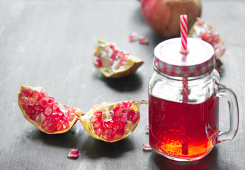 Fresh ripe pomegranate and glasses of pomegranate juice on black wooden table