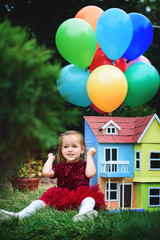 Fototapeta na wymiar Little girl in a beautiful park with gel ballons and a little house.