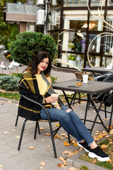 beautiful girl in yellow sweater drinking coffee outside