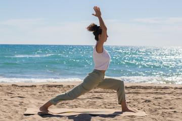 Fototapeta na wymiar Yoga teacher doing some yoga exercises by the beach. Morning routine.