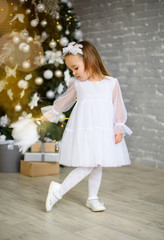 Fototapeta premium Little girl in a beautiful white dress and carnival mask. New year.