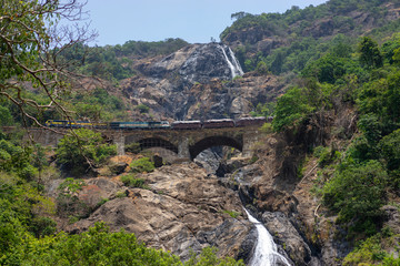 Fototapeta na wymiar Train on the railway bridge on the background of the Dudhsagar Falls