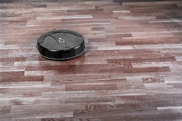 Robot vacuum cleaner on dark laminate floor, modern smart home robotics wireless cleaning device...