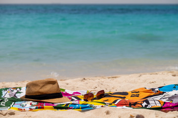 Pareo de playa , sombrero y gafas en una playa desierta junto al mar en el atardecer.