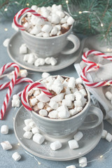 Mugs filled with hot chocolate and marshmallows and candy cane