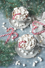 Cups of creamy hot chocolate with melted marshmallows and  candy cane