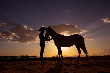 Fototapeta na wymiar Silueta de vaquero con su caballo en el atardecer 